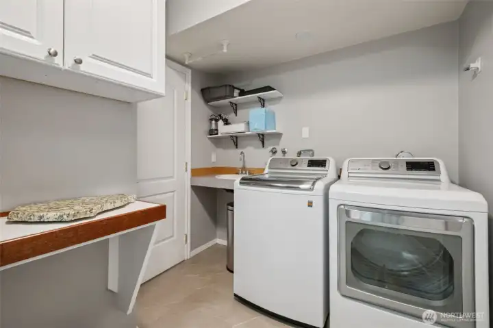 Functional laundry room off the kitchen and garage with built-in shelving and plenty of workspace.