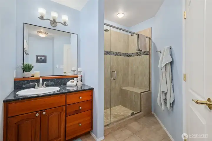 Hall bathroom featuring a wood vanity, modern lighting, and glass-enclosed shower.