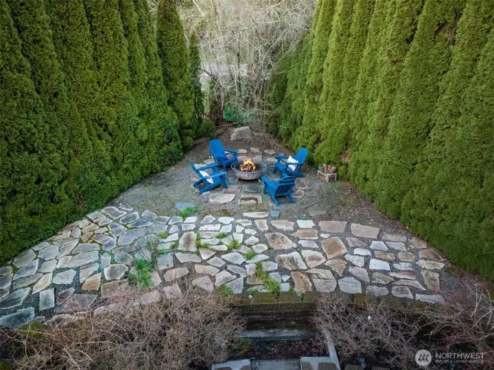 Secluded stone patio surrounded by mature hedges for added privacy.