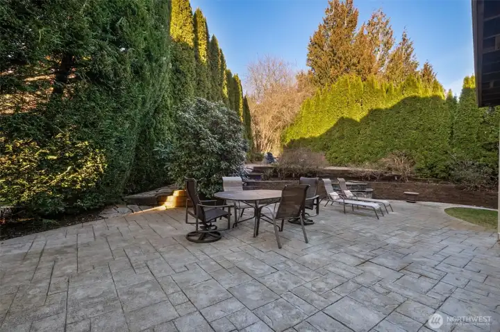 Spacious paved patio with outdoor seating with beautiful mature landscaping.