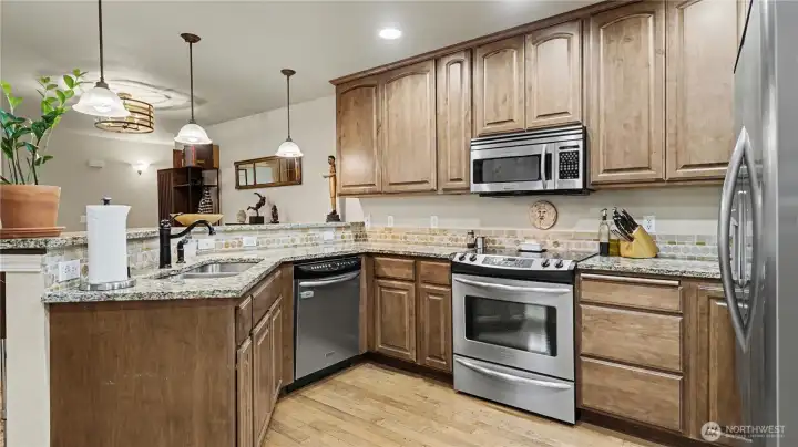 Inviting open kitchen with warm cabinetry, stainless steel appliances, and generous storage throughout.