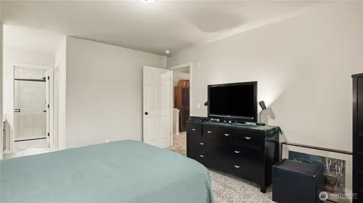 Another view of the primary bedroom featuring en-suite bathroom and walk-in closet.