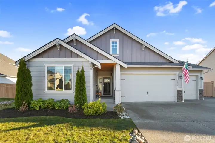Inviting front exterior with clean lines, a covered entry, and a spacious 3-car garage. Thoughtful landscaping and a wide driveway create a polished first impression with functional parking space.