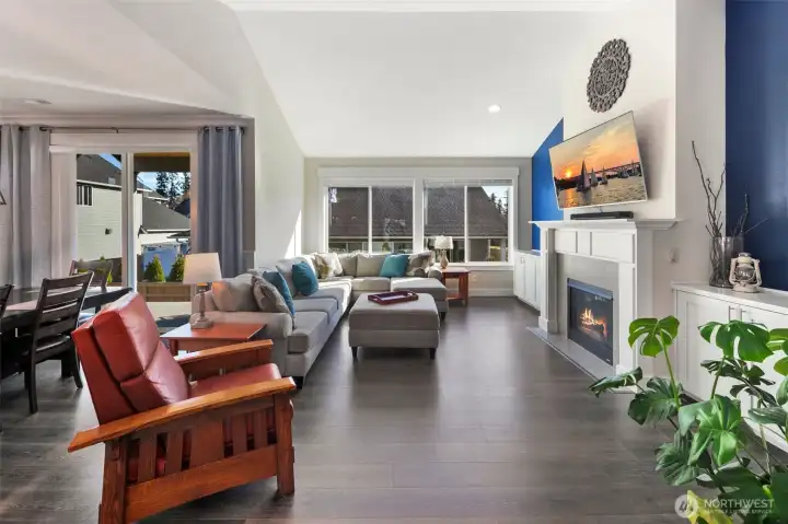 Bright and open living space with vaulted ceilings and expansive windows that bring in natural light throughout the day. The layout creates a comfortable setting for both relaxing and gathering.