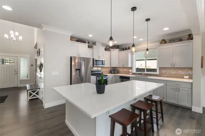 From this angle, the kitchen feels open and connected, with pendant lighting and an oversized island that works for both prep and casual seating.