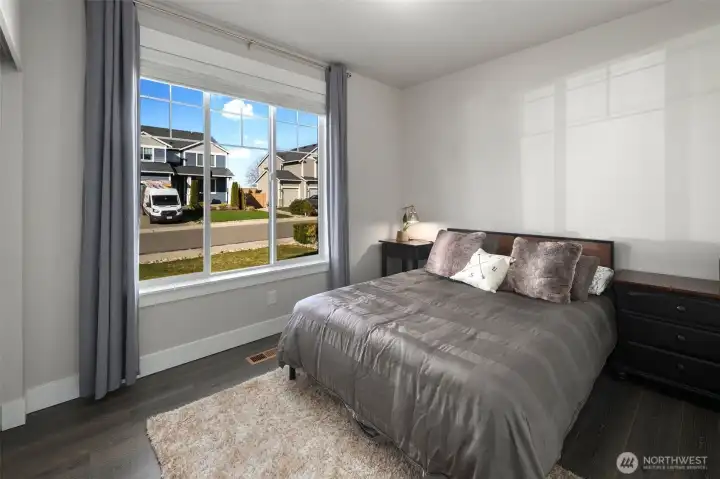 Bright bedroom with a large front-facing window, filling the space with natural light and neighborhood views.