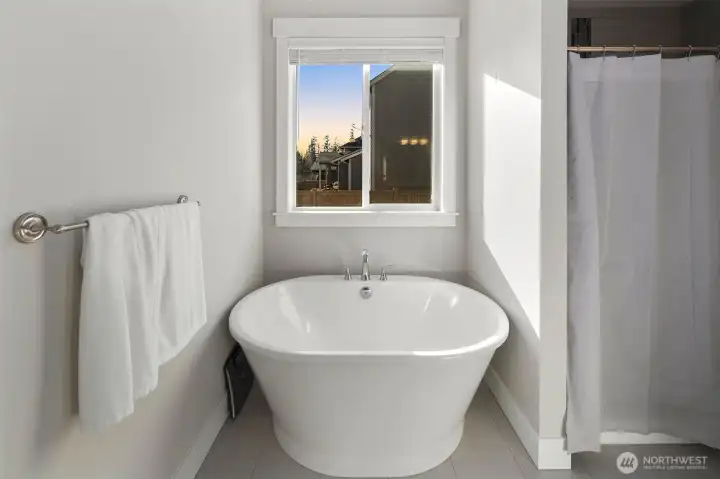 Spa-like soaking tub positioned beneath a window, perfect for relaxing at the end of the day.