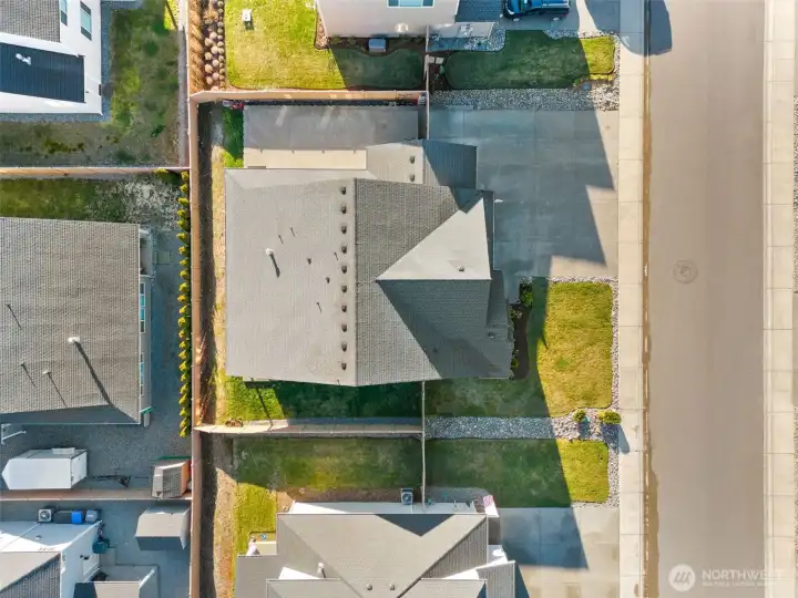 Aerial view highlighting the full property layout, including fenced yard, covered patio, and extended driveway.