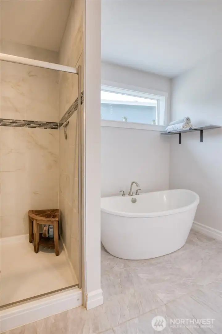 Deep freestanding soaking tub paired with a large tiled walk-in shower. Perfect for a long soak, or a quick start to your day.
