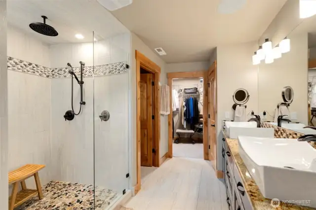 Primary bath with large tile shower, double vanity with granite counters, 2 storage closets, leading to primary closet with lots of natural light from the window