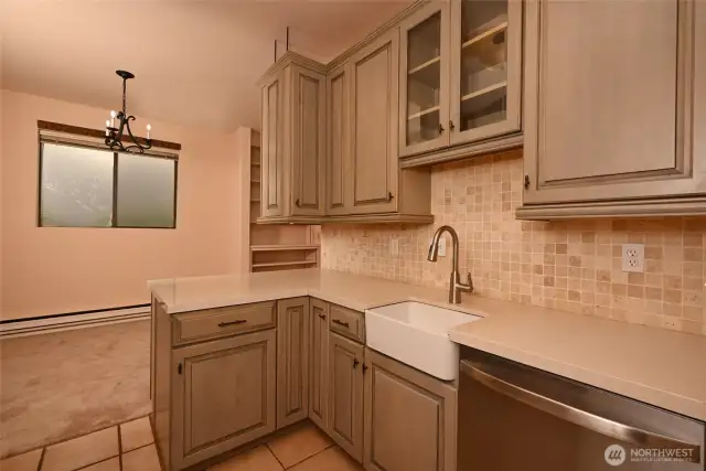 A photo of the kitchen looking into the dining room. There is under-cabinet lighting.