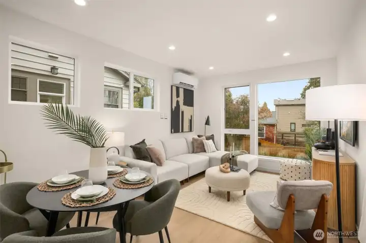 The open-concept great room flows seamlessly from the kitchen to the dining area, anchored by massive windows that flood the space with natural light