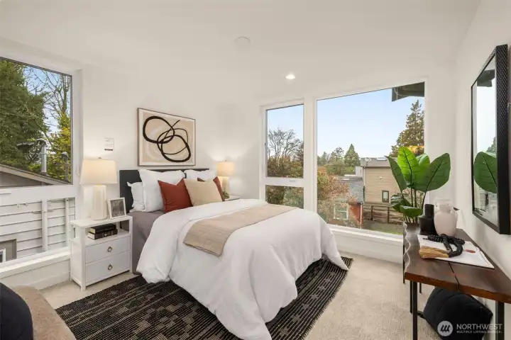 Retreat to the spacious primary suite, where large windows frame peaceful views and create a serene atmosphere for rest