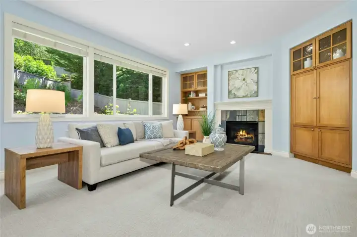 oversized family room with gas fireplace, custom built-ins and a wall of light flooding windows.
