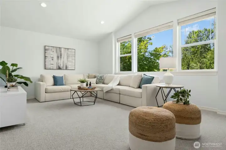 An expansive upper-level bonus room, with a tall ceiling and light filling windows.