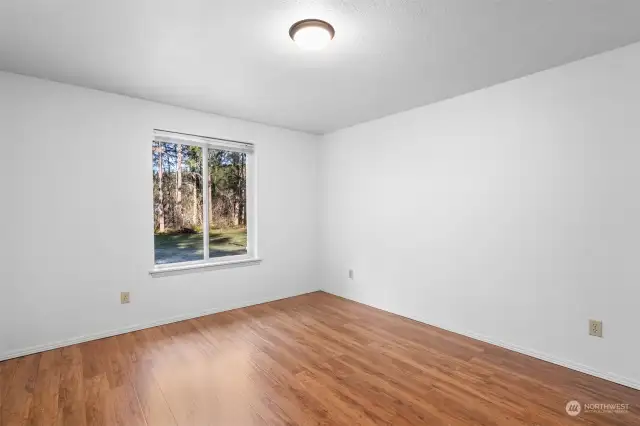 One of two guest bedrooms. Views out the window into the back yard, surrounded by tall trees.