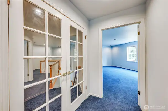 The private primary suite is entered through French doors