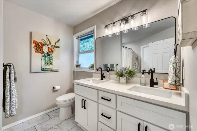 Primary bath with new double sink vanities, quartz tops, flooring, paint and lighting.