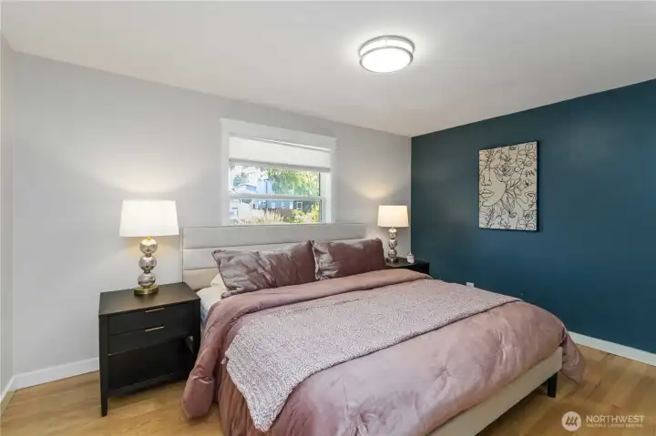 Spacious primary bedroom featuring a bold  accent wall, durable vinyl flooring, and  abundant natural light.