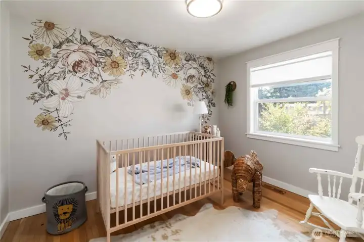 Charming second bedroom with a delightful  floral accent wall, natural light, and versatile  space for your needs.