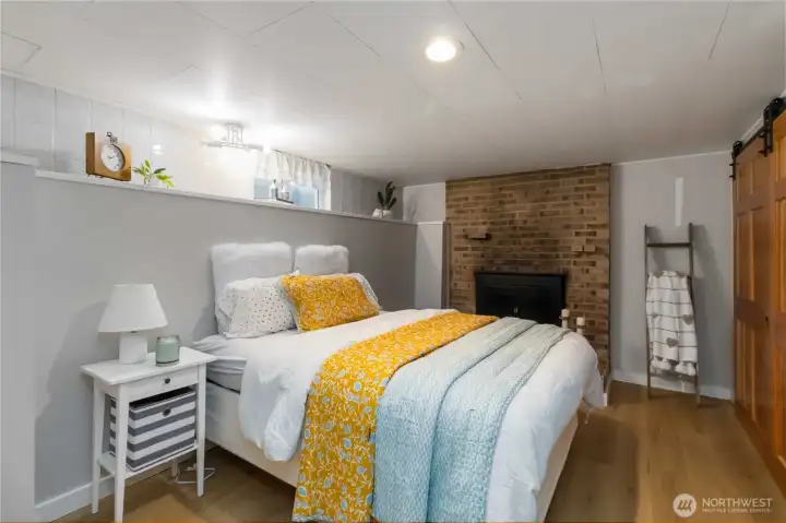 Cozy lower-level spare room featuring a  warm wood-burning fireplace, perfect for  guests or relaxation.