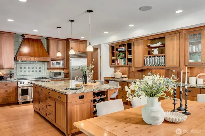 Open kitchen with stainless steel Wolf range, Sub-Zero refrigerator, and plenty of storage, shelves, and granite counters