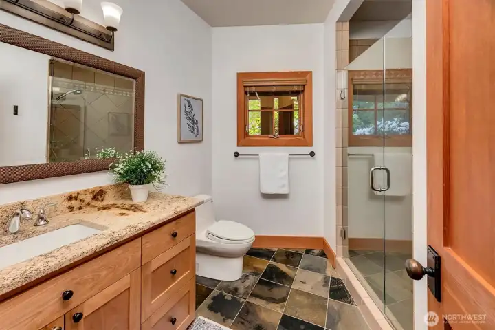Main level three-quarter bath with granite counters, slate floors serves the bedroom wing