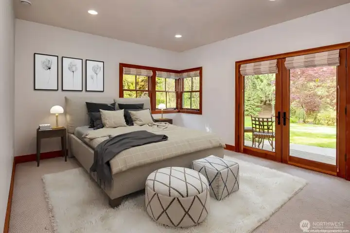 Second main level bedroom with doors opening to the covered deck, patio and gardens