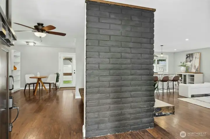 Grand brick adorned fireplace separates great room + flex space.