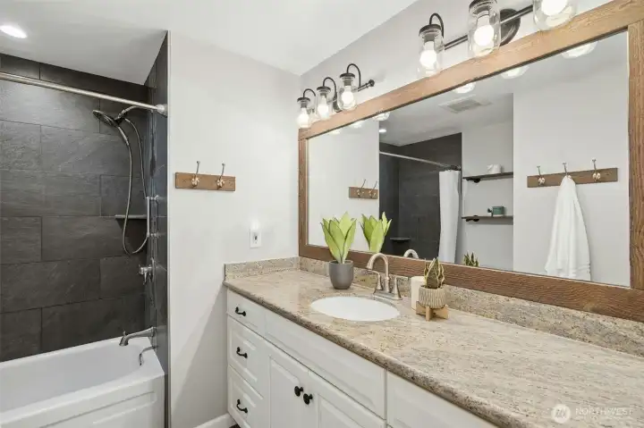 Full bathroom with stone tile, granite countertops and enduring appeal.