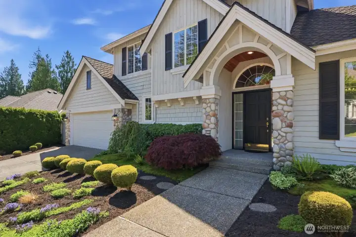An inviting arched entry, stone accents, and lush garden details create a warm welcome before you even step inside.