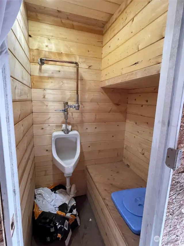 Bathroom with urinal and potty that go into a large bucket, that has no odor after use of a substance that covers it and breaks it down. Easily converted to bathroom with addition of septic system.
