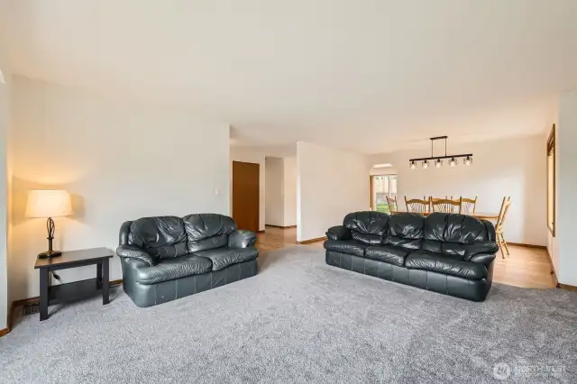 ELEGANT LIVING ROOM WITH GAS FIREPLACE, OPEN FLOOR PLAN, AND ABUNDANT NATURAL LIGHT.