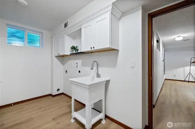 The laundry room has built in cabinets and a utility sink for organization and functionality.