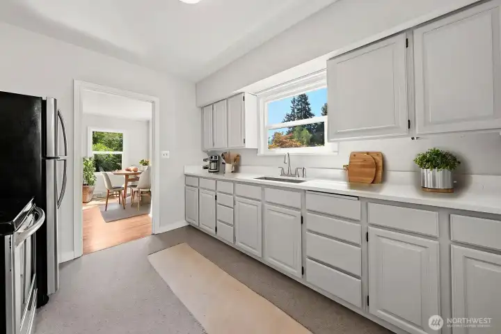 Kitchen with Dining Table in the adjoining room.    Kitchen has lots of cabinet space. Efficient use of space with the appliances and sink all near each other.  (virtually staged)