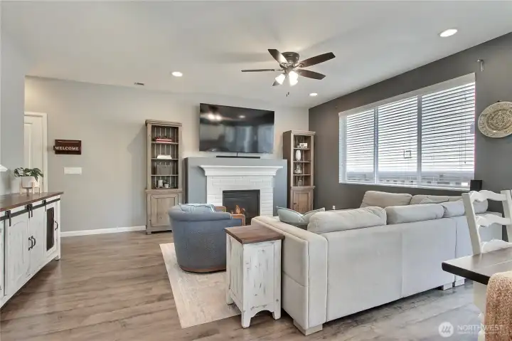 View of your family room from the kitchen. Love the large windows, the flooring, the ceiling fan and gas fireplace to keep you comfortable year-round.