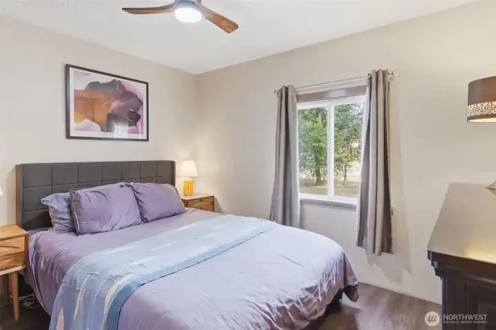 Main floor bedroom with ceiling fan and view to side yard