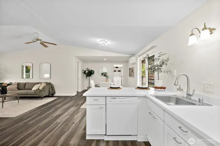 L shaped kitchen layout with refreshed white cabinets and countertops. Dishwasher located to the left of sink.