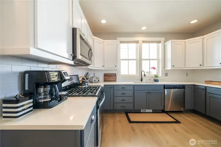 View 1 of spacious kitchen with quartz countertops, engineered wood floors, stainless steel appliances and gas stove.