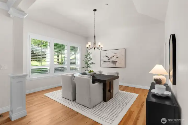 Formal dining area with vaulted ceilings, hardwood floors, and large windows.