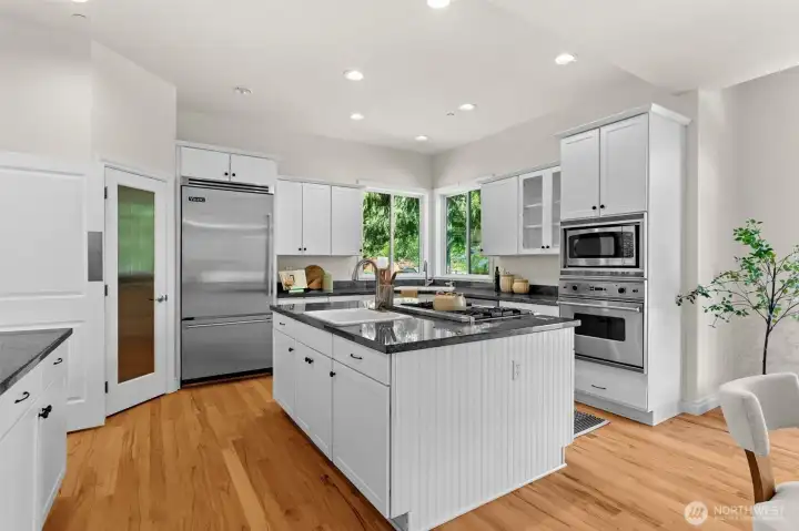 Bright and welcoming kitchen with generous prep space, large island, and views of the surrounding greenery.