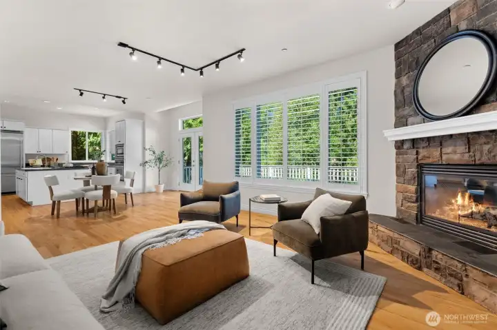 Open living area with stone fireplace, generous windows, and seamless connection to the kitchen and dining spaces.