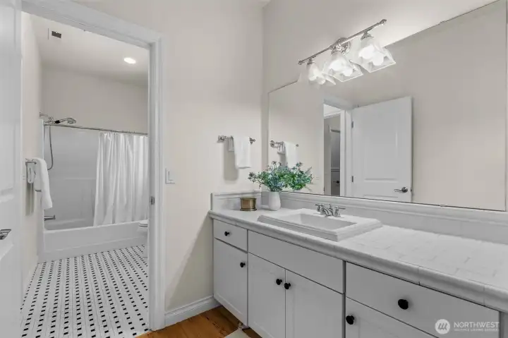 Bathroom features extended vanity, updated lighting, and access from adjacent bedrooms.
