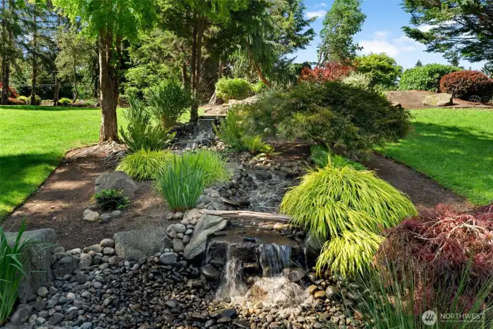 Thoughtfully designed landscaping highlights natural stone accents and cascading water feature.