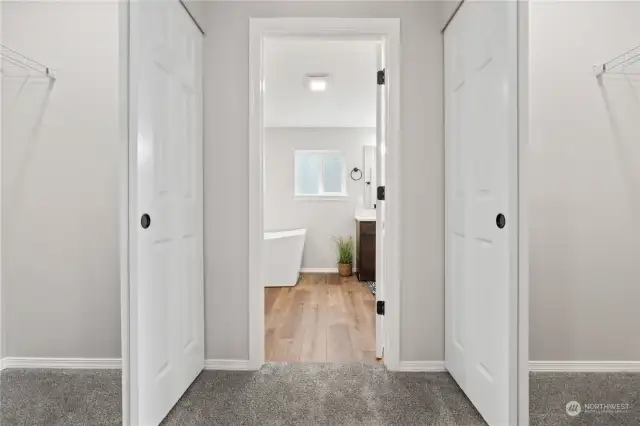 Primary Bedroom w/Double Walk-In Closets on either side of the hallway leading to the En Suite Bath.