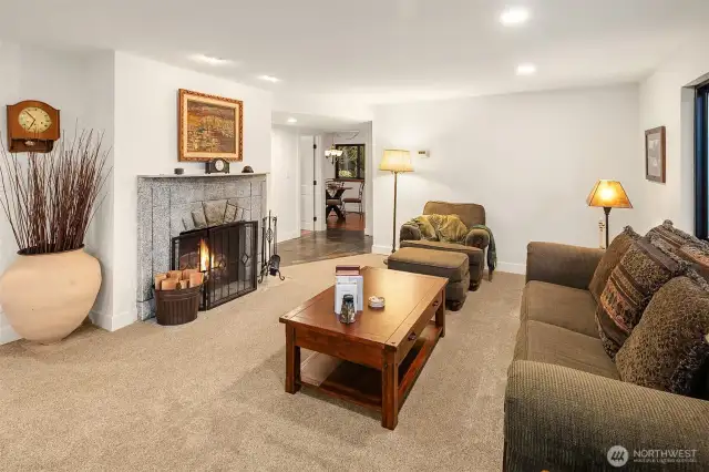 Wood burning fireplace as seen from the dining area. Hallway ahead leads to a full bath, utility room, then around to the kitchen, creating a circular floorplan that begs you to entertain.