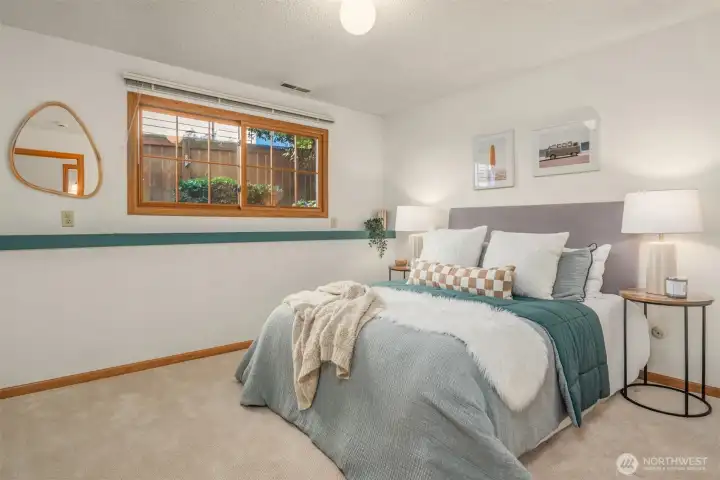 A comfortable and well-appointed lower level bedroom featuring soft neutral tones, plush carpet, and a charming window that brings in natural light — complete with its own ¾ bathroom, making it a quiet, private retreat with excellent potential for a self-contained mother-in-law suite.