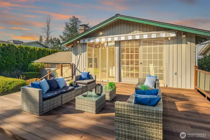 A expansive back deck just off the family room, featuring comfortable outdoor lounge seating and all framed by lush mature landscaping — an ideal setting for outdoor entertaining or relaxed al fresco living.
