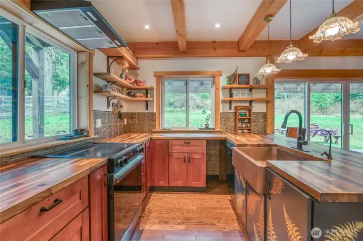 From the entry, the kitchen is filled with sunlight, walnut countertops, Teredo wood detailing at the seating area, and handcrafted Spanish tile.
