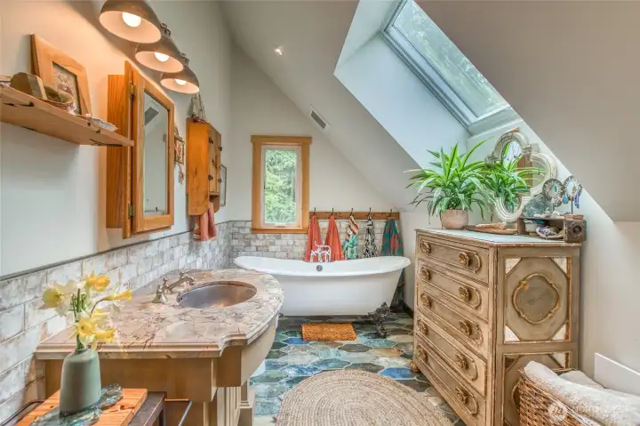 Bathroom with custom tile and a clawfoot tub, large skylight, plus a washer and dryer in the room (just not in the picture).